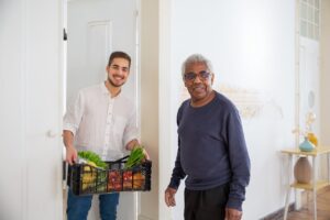 A home health aide brings groceries to a senior care client.